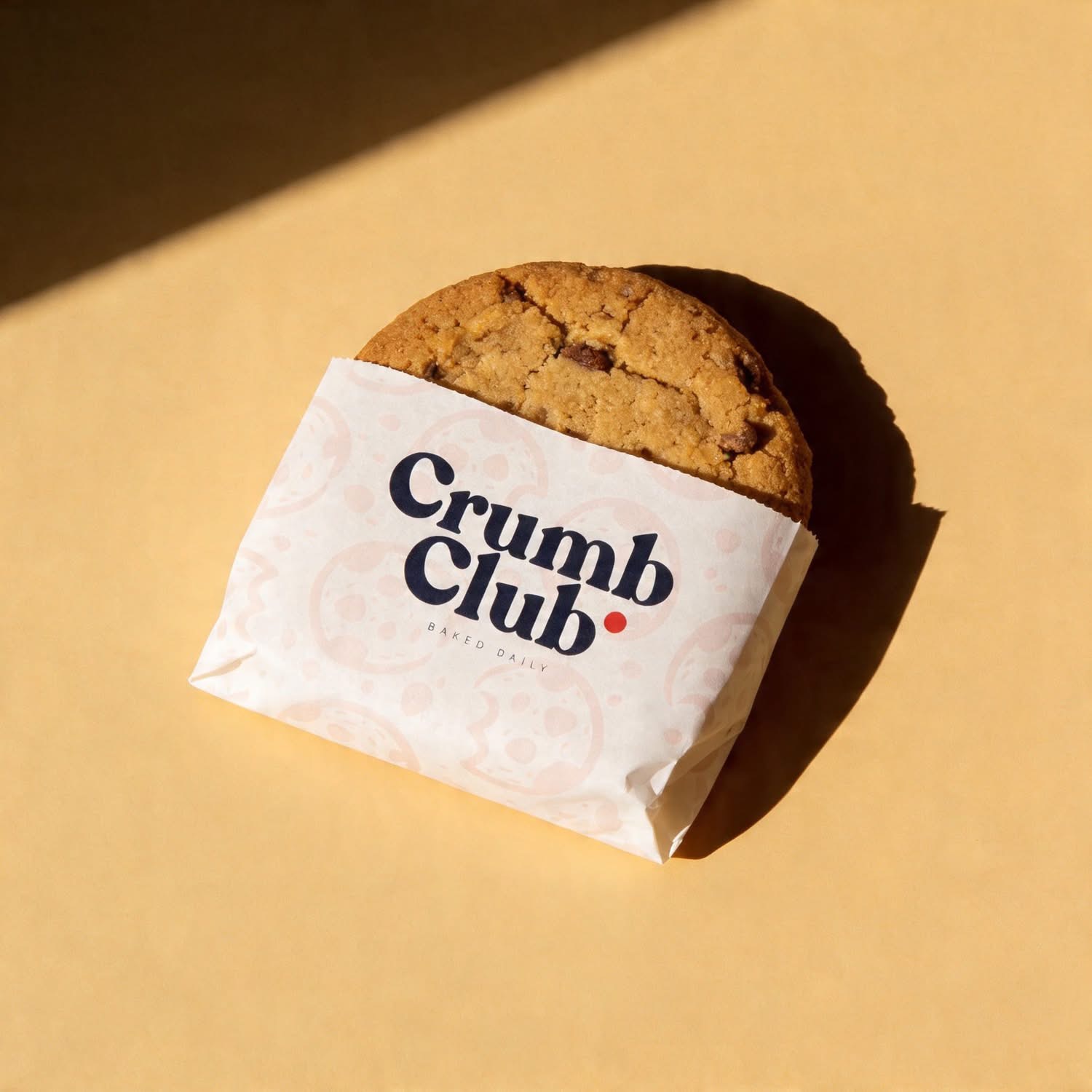 Crumb Club — Packaging: Branded cookie sleeve in warm sunlight
